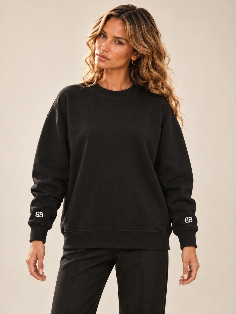 Lily wears a black oversized crewneck with small BB embroidery at both wrists and a plain chest.