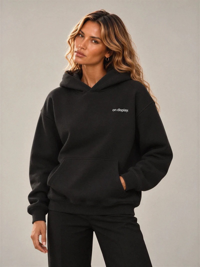 Lily wears the black Signature Heavy Hoodie with a small white on display. wordmark at the left chest.